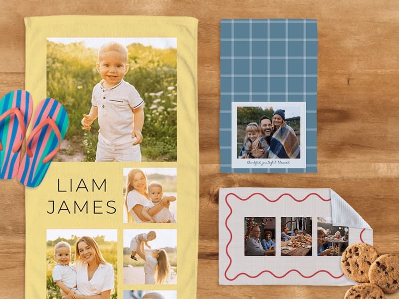 Personalized photo towels on a wood surface: a yellow beach towel with photos of a boy and 'Liam James' text, a blue plaid towel with a family portrait reading 'thankful grateful blessed,' and a white scalloped-edge towel with family dinner photos.